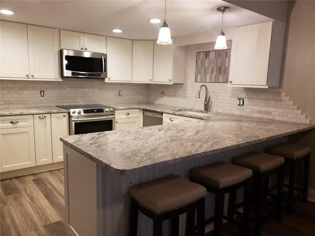 a kitchen with stainless steel appliances granite countertop a stove top oven a sink a microwave and white cabinets