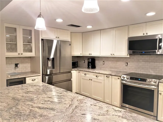 a kitchen with stainless steel appliances granite countertop a stove a refrigerator and a microwave