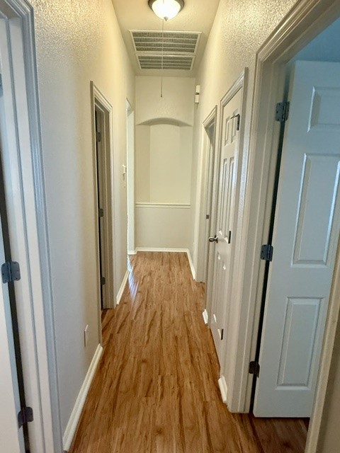 20724 Kearney Hill Road Pflugerville, TX 78660 - Photo 32 of 40 Hallway featuring wood-finish flooring, white baseboards, and neutral wall paint