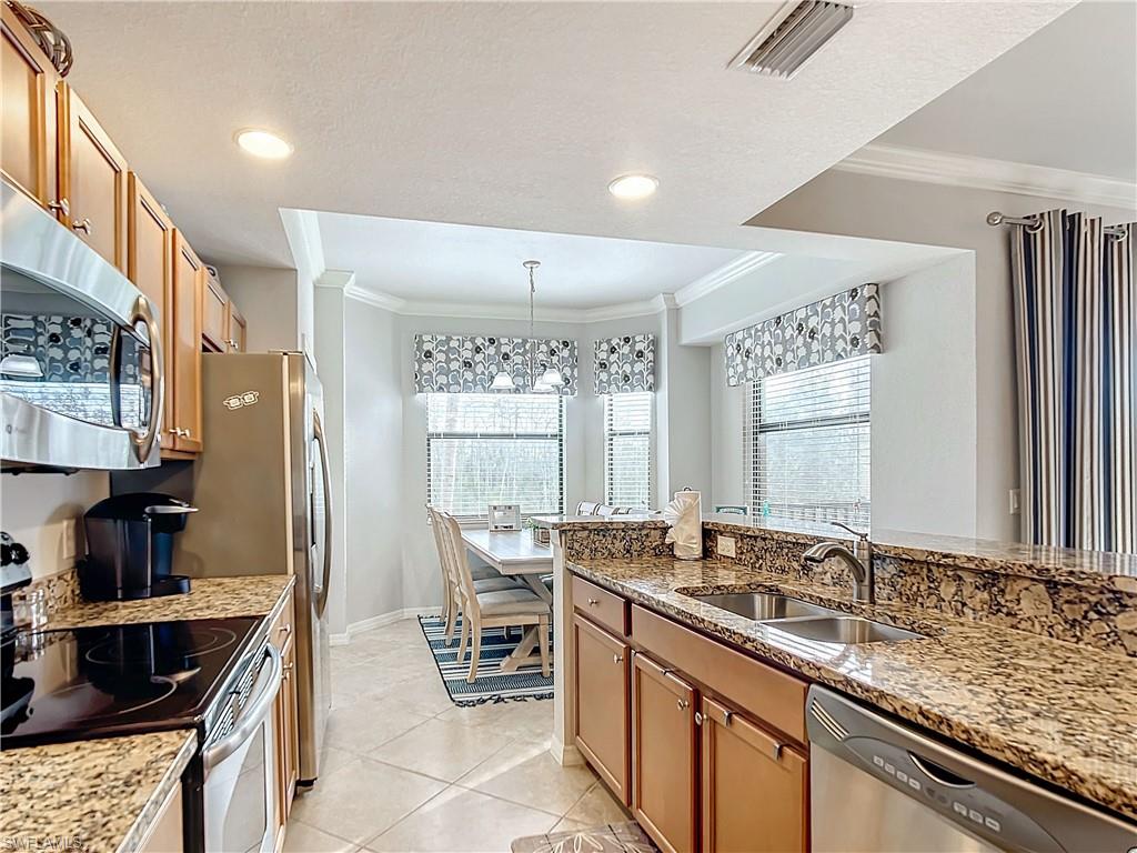 9715 Acqua Court, Unit 127 Naples, FL 34113 - Photo 12 of 50 a kitchen with stainless steel appliances a sink stove and cabinets