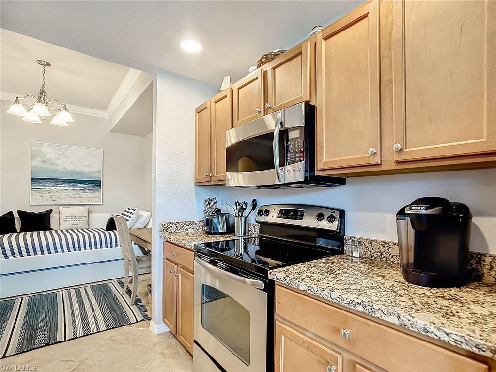 9715 Acqua Court, Unit 127 Naples, FL 34113 - Photo 15 of 50 a kitchen with stainless steel appliances granite countertop a stove a sink and a microwave