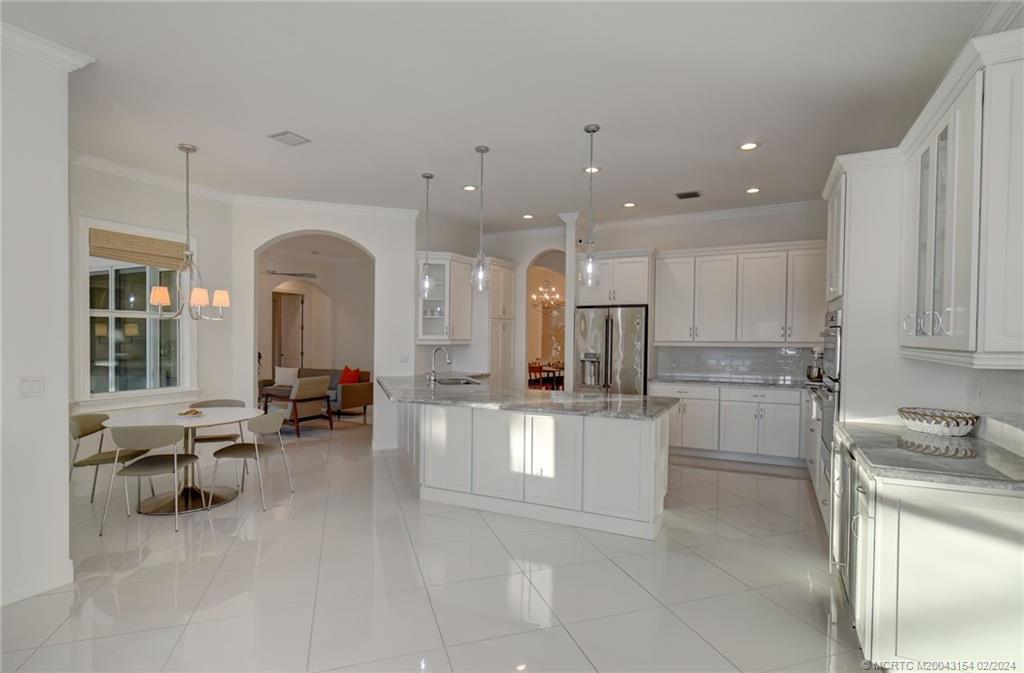 7172 Southeast Pierre Circle Stuart, FL 34997 - Photo 14 of 43 a large white kitchen with a large window and chairs