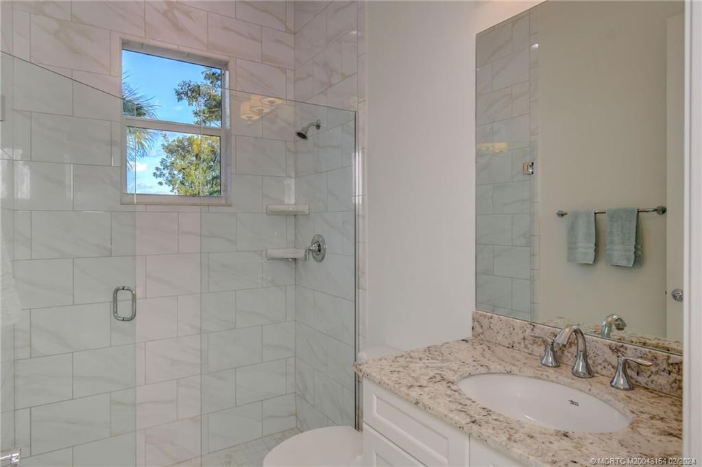7172 Southeast Pierre Circle Stuart, FL 34997 - Photo 17 of 43 a bathroom with a granite countertop sink a toilet and shower