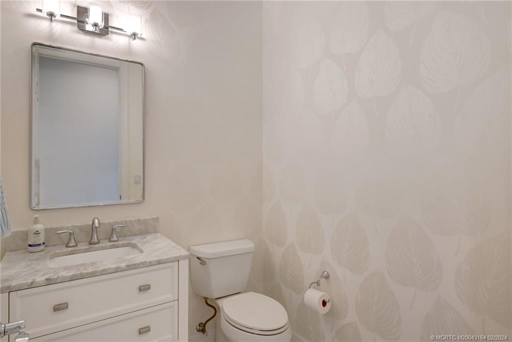 7172 Southeast Pierre Circle Stuart, FL 34997 - Photo 24 of 43 a bathroom with a granite countertop toilet sink mirror and vanity