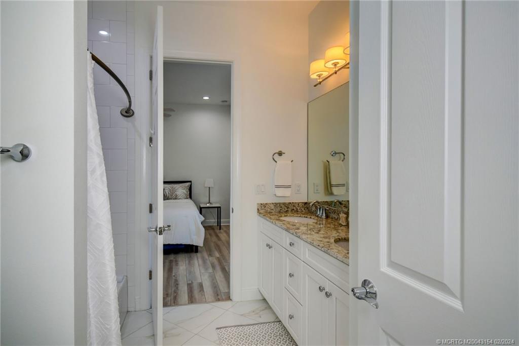 7172 Southeast Pierre Circle Stuart, FL 34997 - Photo 28 of 43 a en suite bathroom with a granite countertop sink and a mirror