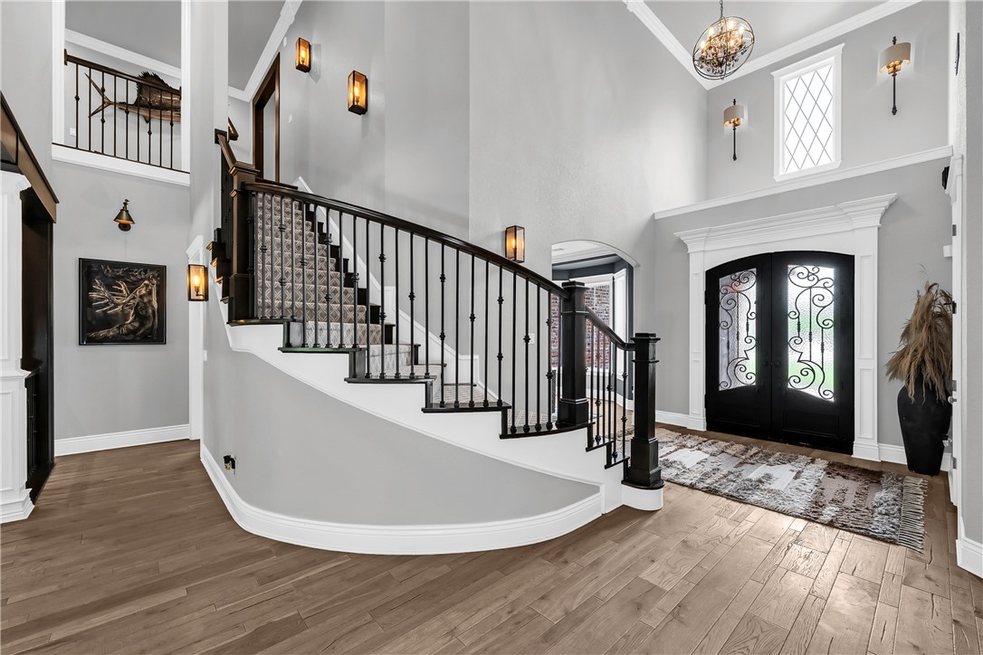 3510 Copper Ridge Road Rogers, AR 72756 - Photo 45 of 58 Grand entryway featuring hardwood floors, a curved staircase with a dark wood banister and patterned runner, and a double entry door with decorative ironwork