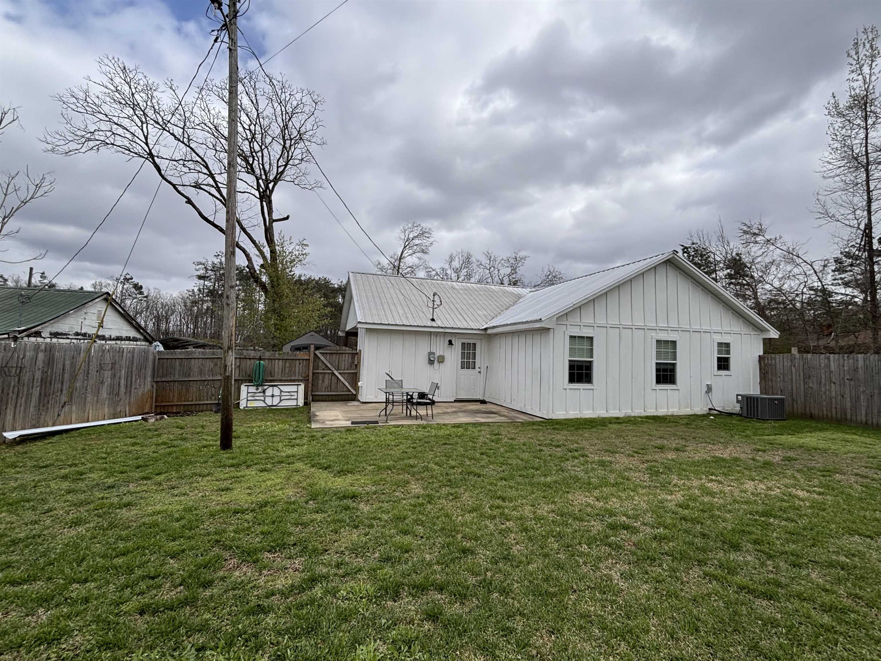 67 Cr 306 Road Iuka, MS 38852 - Photo 23 of 23 Back of house with board and batten siding, a fenced backyard, a patio, and a metal roof