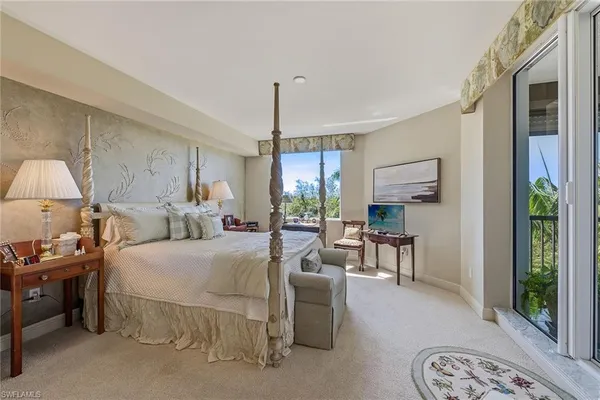 a bedroom with a bed a mirror on dresser and a chandelier