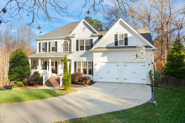 a view of a white house next to a yard with big trees
