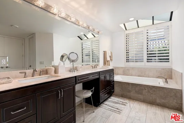 a bathroom with a double vanity sink a large mirror and bathtub