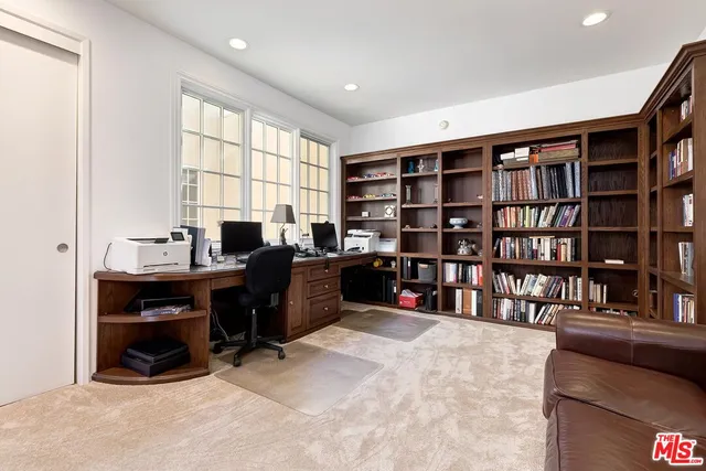 a view of a workspace with bookshelf and a window
