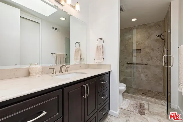 a bathroom with a shower sink vanity granite and mirror