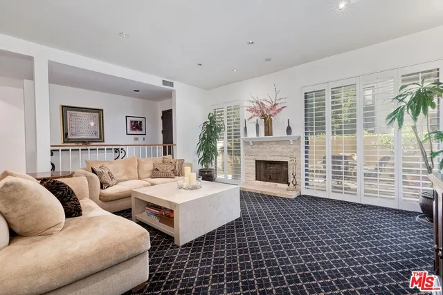 a living room with couches a fireplace and a large window