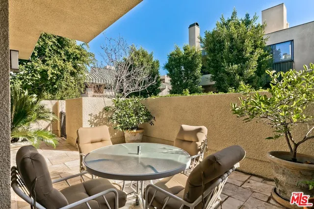 a backyard of a house with table and chairs potted plants