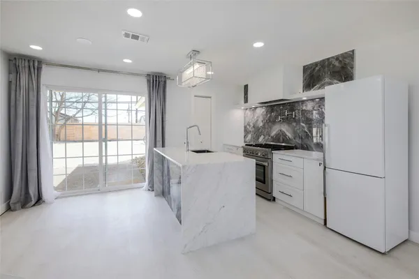 a kitchen with stainless steel appliances kitchen island granite countertop a refrigerator and a stove top oven