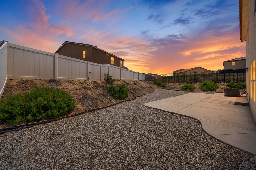 20130 Curaco Court Riverside, CA 92507 - Photo 2 of 43 Backyard with gravel landscaping, concrete patio, shrubs, and perimeter fencing.