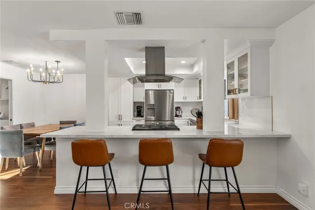 a kitchen with stainless steel appliances kitchen island a large white table and chairs in it