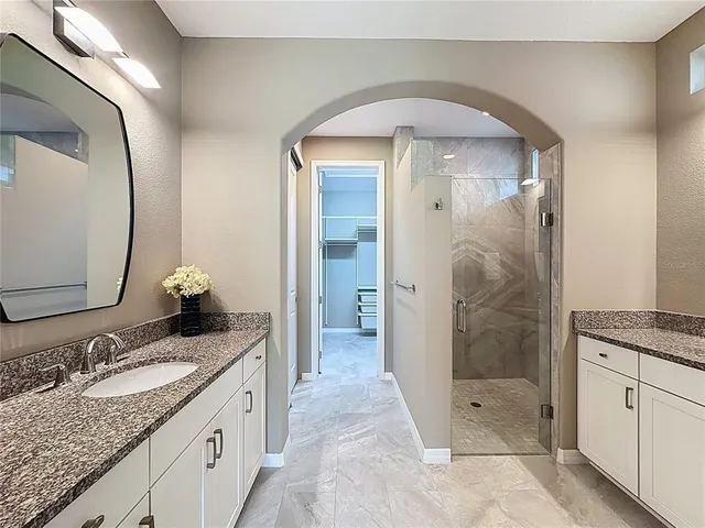 a spacious bathroom with a granite countertop sink a mirror and a shower