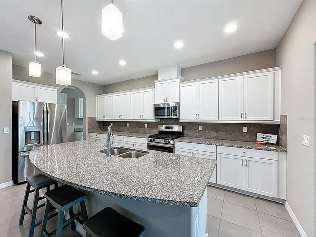 a large kitchen with granite countertop lots of stainless steel appliances granite countertop a stove a sink and a granite counter tops