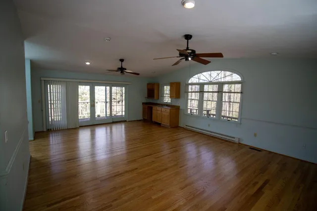 an empty room with wooden floor and windows