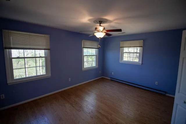 a view of an empty room with a window and wooden floor