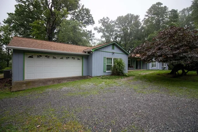 a view of a house with a yard and large trees
