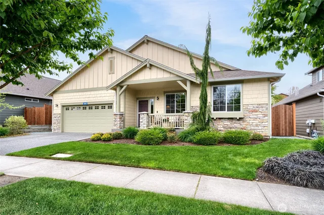 a view of a white house next to a yard with potted plants