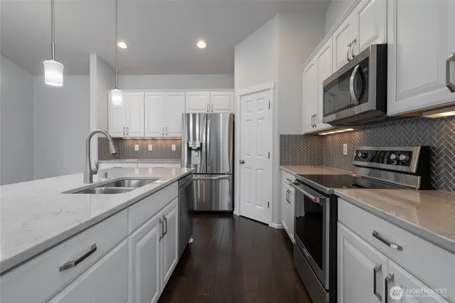 a kitchen with stainless steel appliances granite countertop a sink a stove a refrigerator and a refrigerator with wooden floor