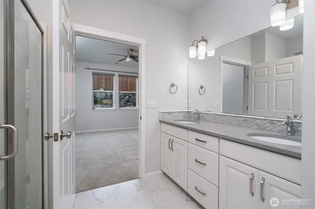 a bathroom with a granite countertop sink two mirror and a shower