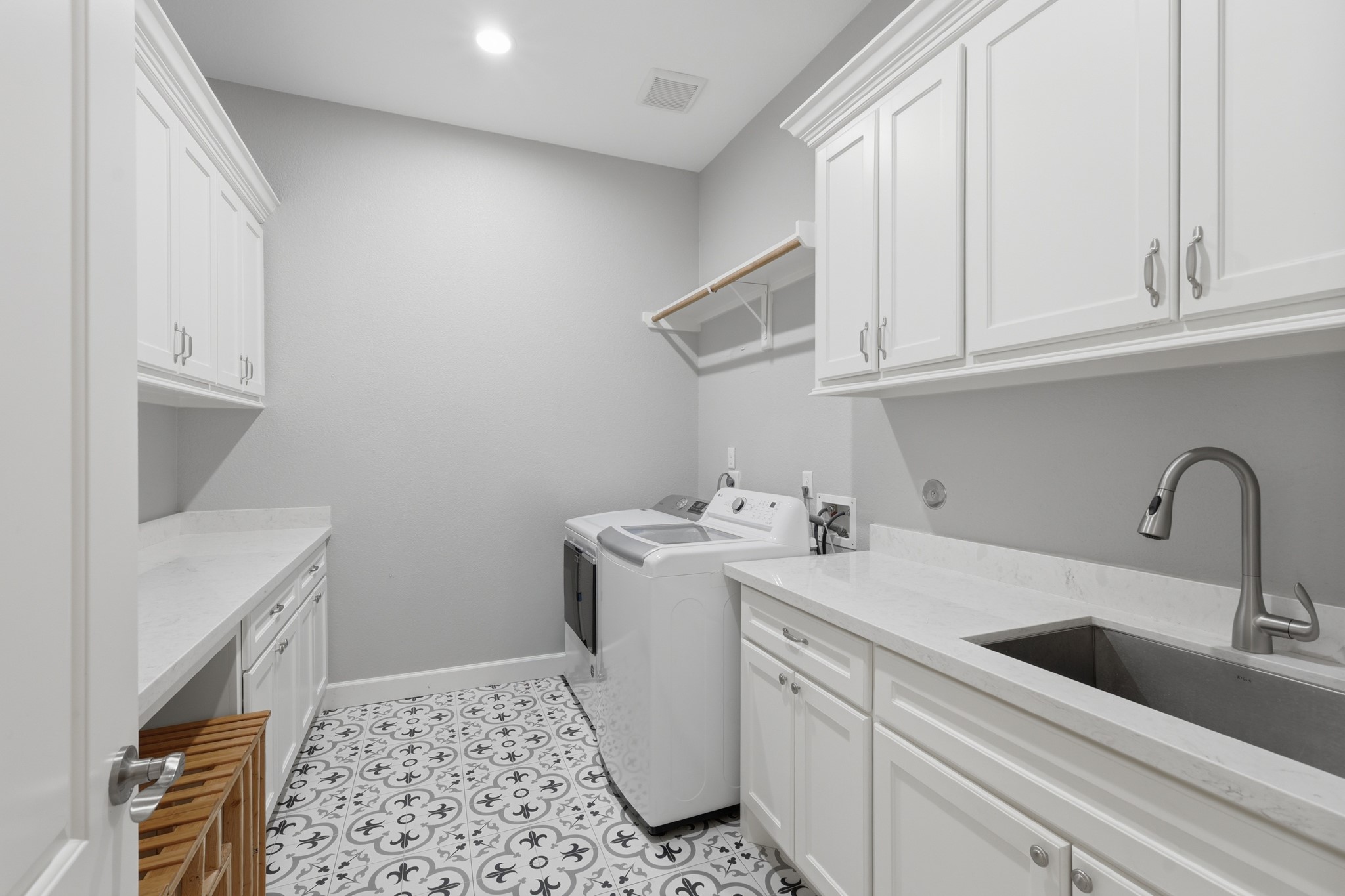 7106 Hampton Court Spring, TX 77389 - Photo 28 of 31 Laundry room featuring white cabinetry, a spacious countertop with a sink, tile flooring with a stylish pattern, and a washer and dryer. The space is well-lit and functional, providing ample storage and workspace.