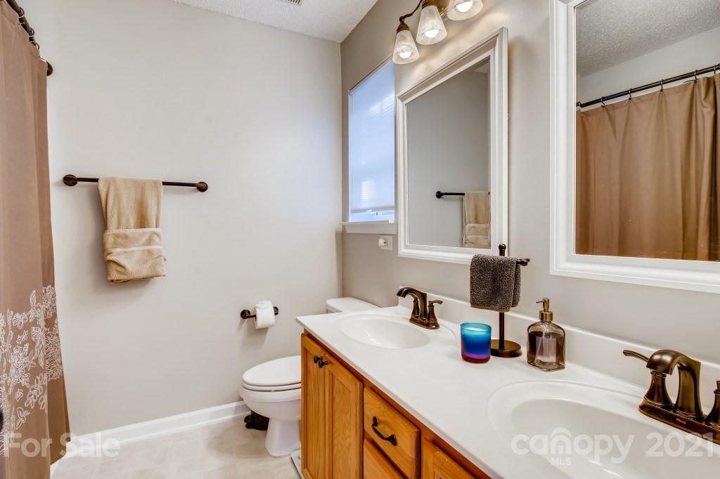 8210 Rudolph Road Charlotte, NC 28216 - Photo 8 of 11 a bathroom with a granite countertop sink a toilet and a mirror