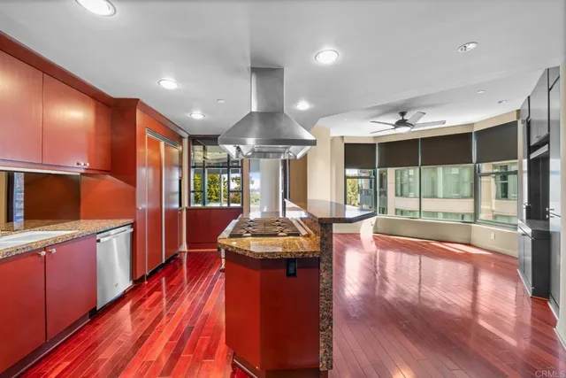 a dining hall with stainless steel appliances granite countertop a stove and a view of living room