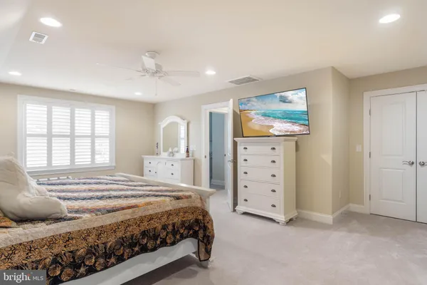 a spacious bedroom with a bed a dresser and a window