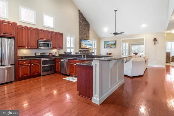 a kitchen with stainless steel appliances granite countertop wooden cabinet a sink a stove and a refrigerator