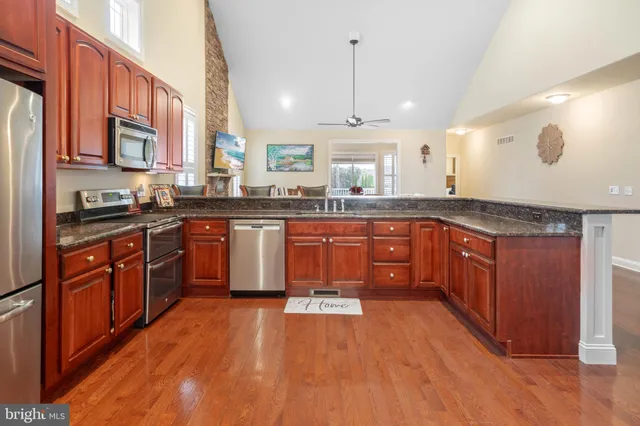 a large kitchen with stainless steel appliances granite countertop wooden floors and granite counter tops