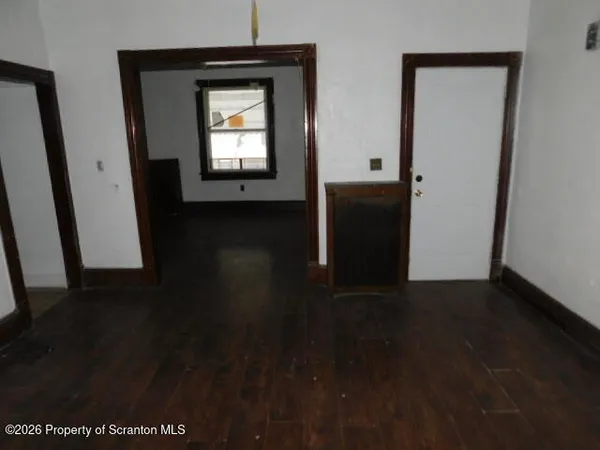 a view of a hallway with wooden floor and a living room