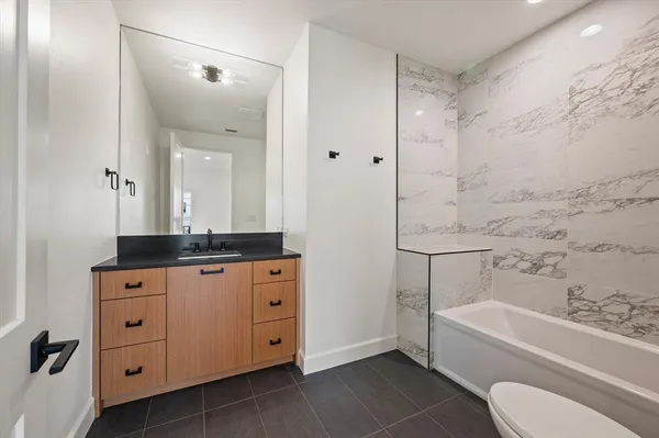 a bathroom with a granite countertop sink a toilet and bathtub