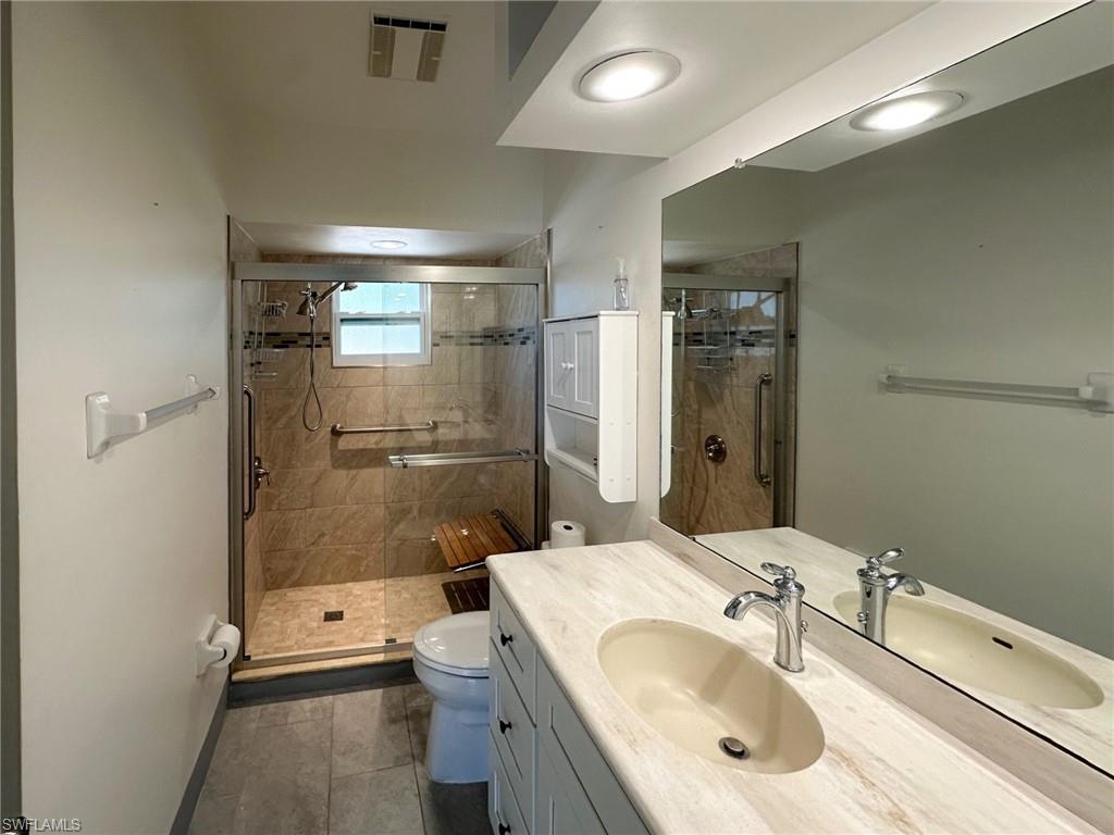 137 Meta Street Fort Myers, FL 33905 - Photo 12 of 50 Bathroom with vanity, a stall shower, and dark tile patterned floors