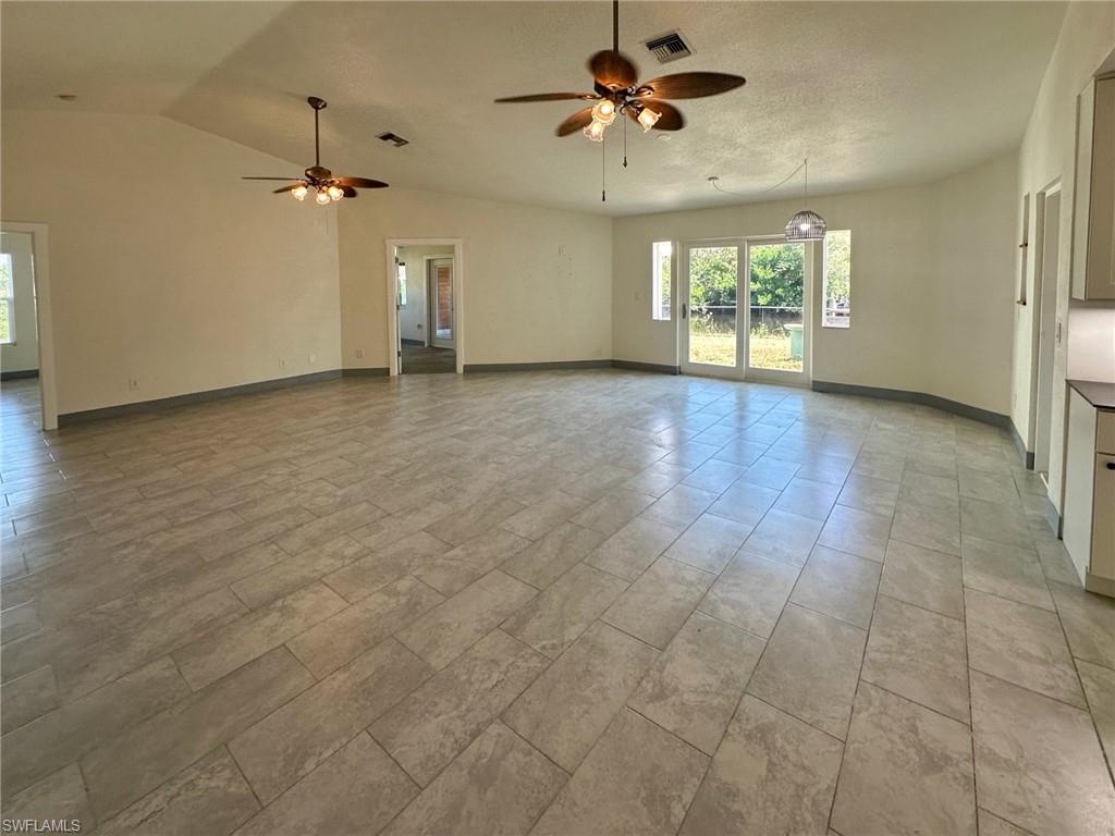 137 Meta Street Fort Myers, FL 33905 - Photo 8 of 50 Unfurnished living room featuring a ceiling fan, vaulted ceiling, and healthy amount of natural light