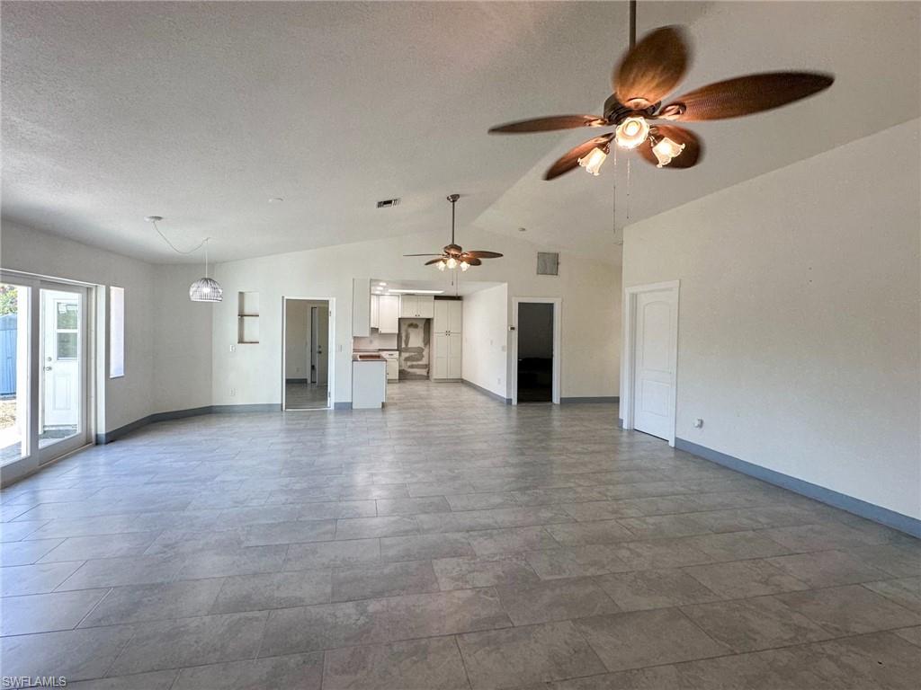 137 Meta Street Fort Myers, FL 33905 - Photo 9 of 50 Unfurnished living room with lofted ceiling, ceiling fan, and a textured ceiling