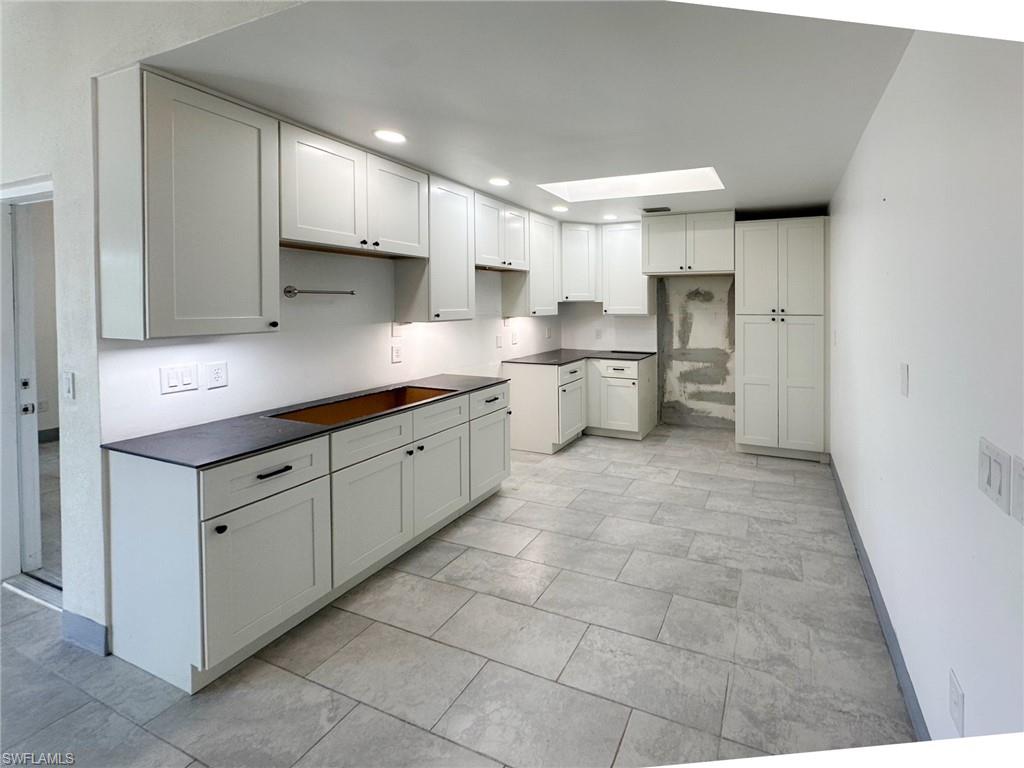 137 Meta Street Fort Myers, FL 33905 - Photo 10 of 50 Kitchen with dark countertops, a skylight, white cabinetry, and recessed lighting