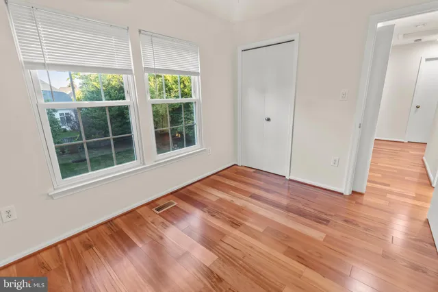a view of empty room with wooden floor and fan