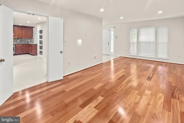 a view of an empty room with wooden floor and window