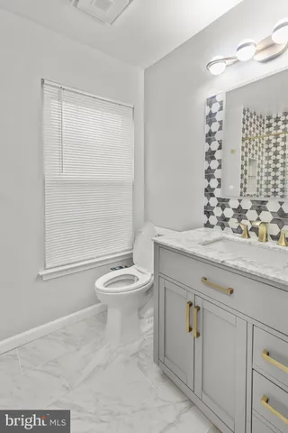 a bathroom with a toilet a sink a vanity and mirror