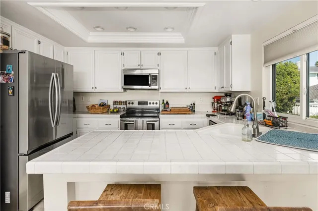 a kitchen with stainless steel appliances a stove a sink a refrigerator a window and white cabinets