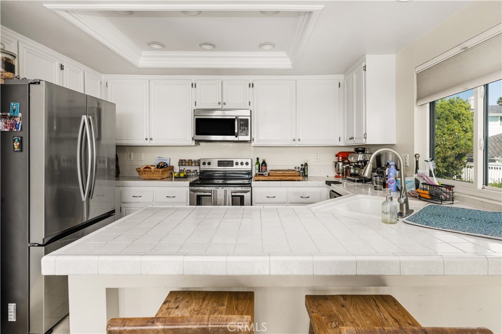 24722 Dana Point Drive Dana Point, CA 92629 - Photo 8 of 17 a kitchen with stainless steel appliances a stove a sink a refrigerator a window and white cabinets