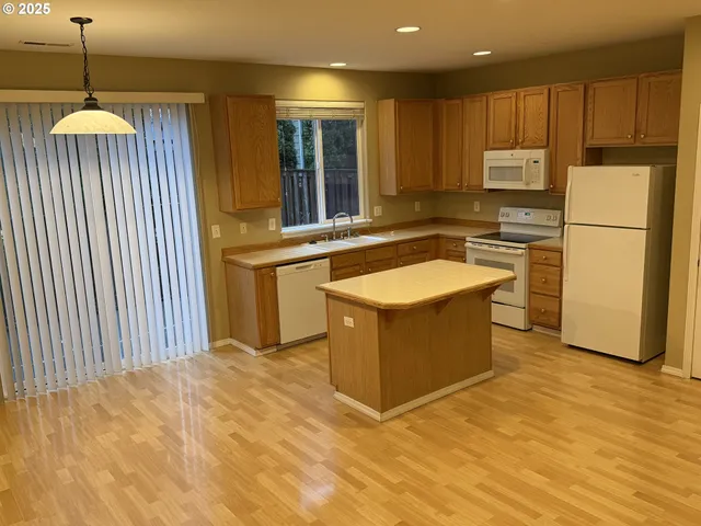 a kitchen with stainless steel appliances granite countertop a stove a sink dishwasher and a refrigerator with wooden floor