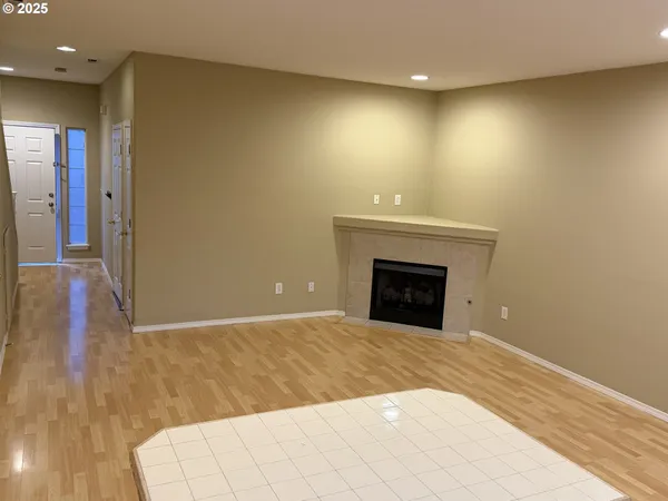 a view of an empty room with wooden floor and a fireplace