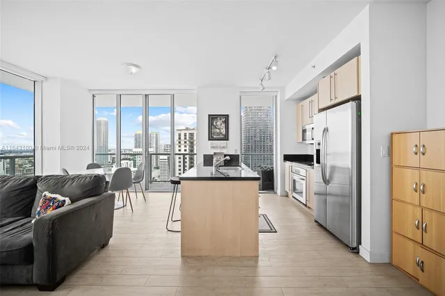 a living room with furniture and a large window with kitchen view
