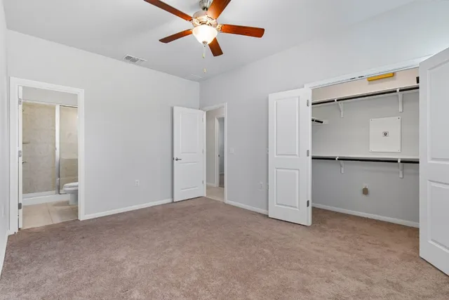 an empty room with closet and a ceiling fan